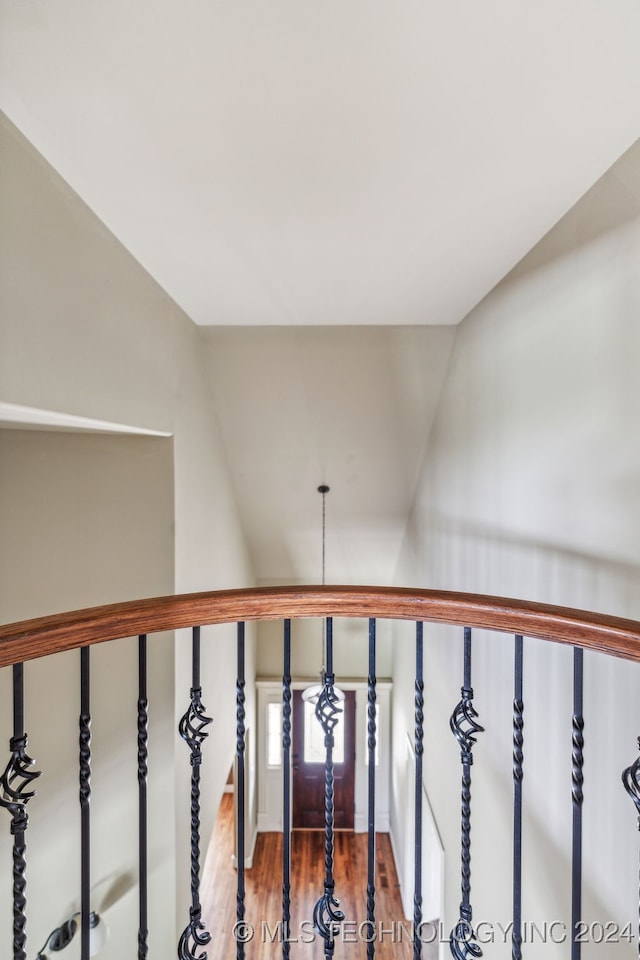 stairs featuring lofted ceiling, a chandelier, and wood-type flooring