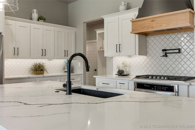 kitchen featuring custom exhaust hood, decorative backsplash, stainless steel appliances, and white cabinets