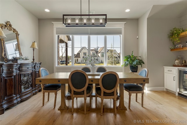 dining space featuring a chandelier, beverage cooler, and light wood-type flooring