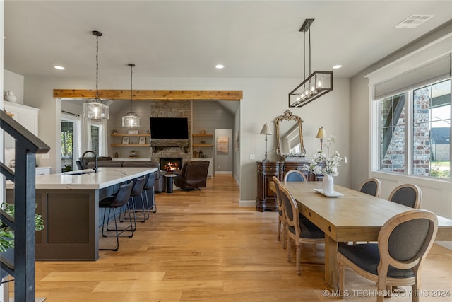 dining area featuring sink, light hardwood / wood-style flooring, a wealth of natural light, and a fireplace