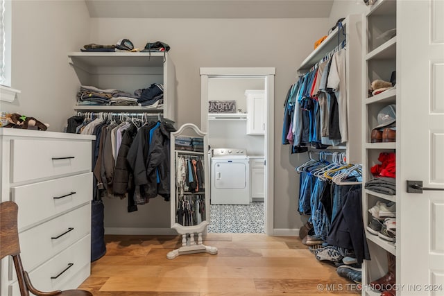 walk in closet with washer / dryer and light hardwood / wood-style floors