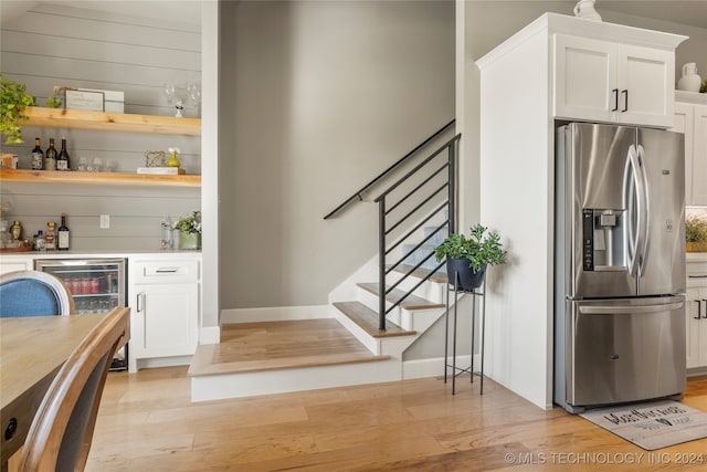 interior space with wine cooler, light hardwood / wood-style flooring, stainless steel fridge, and white cabinets