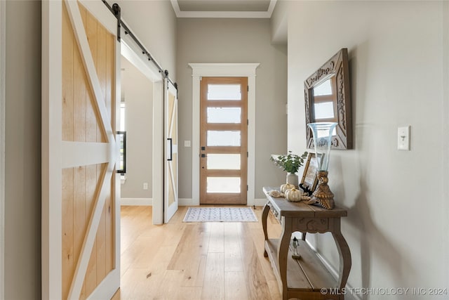 doorway featuring crown molding, light wood-type flooring, and a barn door