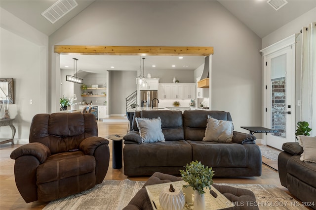 living room featuring sink, light hardwood / wood-style flooring, and high vaulted ceiling