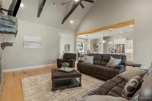 living room featuring beam ceiling, light hardwood / wood-style floors, high vaulted ceiling, and ceiling fan