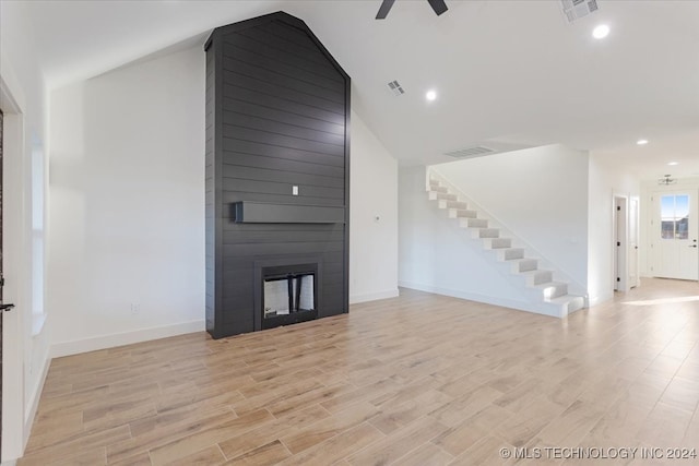 unfurnished living room with a large fireplace, light wood-type flooring, and ceiling fan