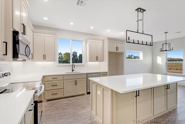 kitchen with a healthy amount of sunlight, appliances with stainless steel finishes, sink, and a kitchen island