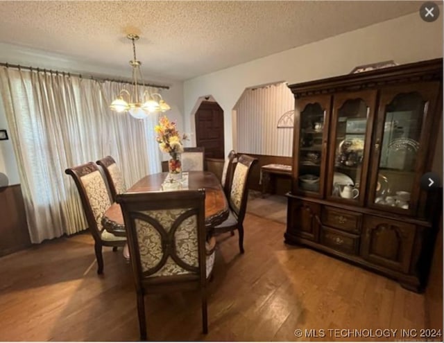 dining room with dark hardwood / wood-style floors, a chandelier, and a textured ceiling