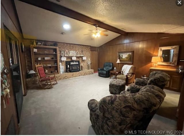 carpeted living room with a wood stove, wood walls, lofted ceiling with beams, and ceiling fan