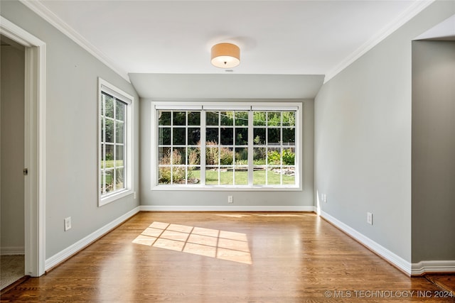 unfurnished dining area with crown molding, vaulted ceiling, and hardwood / wood-style floors