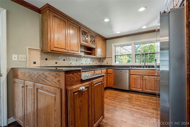 kitchen with light hardwood / wood-style flooring, stainless steel appliances, backsplash, ornamental molding, and sink