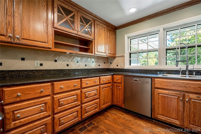 kitchen featuring dark stone counters, ornamental molding, dishwasher, dark wood-type flooring, and sink