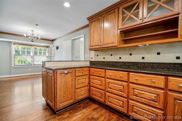 kitchen featuring a notable chandelier, dark wood-type flooring, backsplash, and crown molding