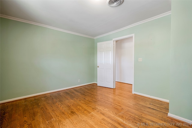 spare room with crown molding and light wood-type flooring