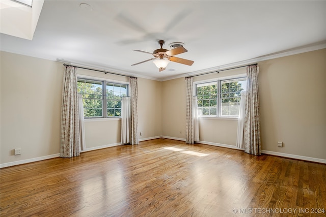 empty room with hardwood / wood-style flooring, ornamental molding, and a wealth of natural light