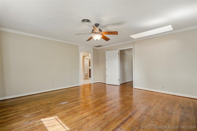 unfurnished room with crown molding, hardwood / wood-style flooring, a skylight, and ceiling fan