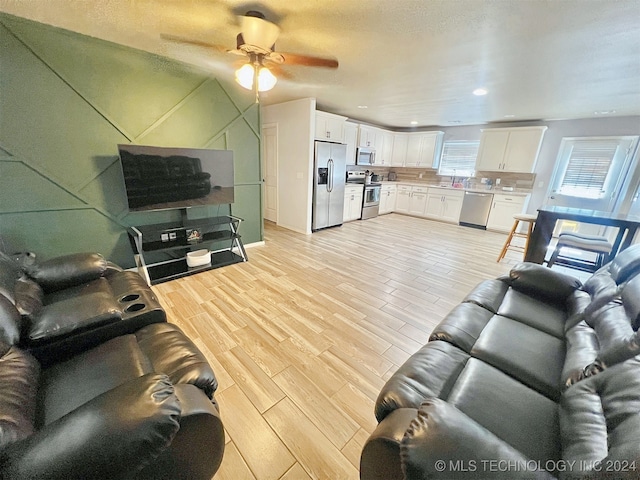 living room featuring light hardwood / wood-style flooring, sink, and ceiling fan