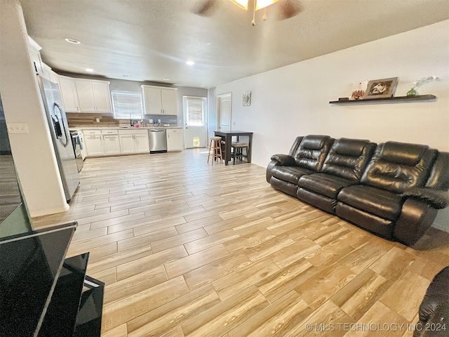 living room with sink, light wood-type flooring, and ceiling fan