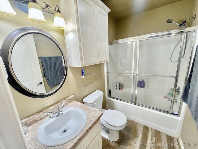 full bathroom with vanity, toilet, wood-type flooring, and enclosed tub / shower combo