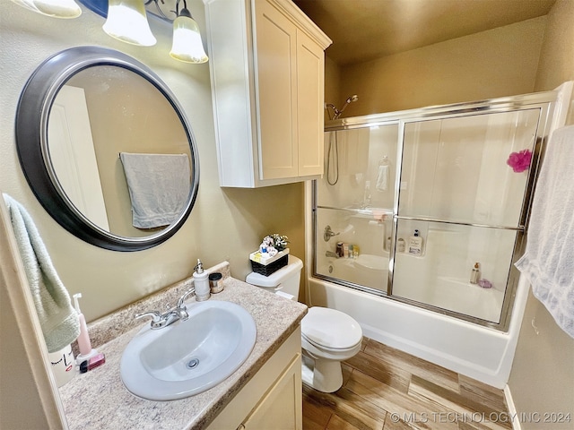 full bathroom featuring vanity, enclosed tub / shower combo, wood-type flooring, and toilet