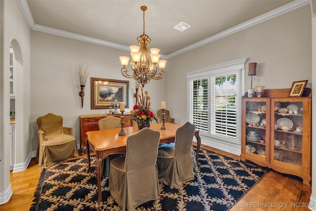 dining space with an inviting chandelier, ornamental molding, and light wood-type flooring