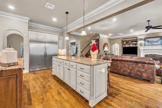 kitchen featuring stainless steel built in fridge, light hardwood / wood-style flooring, a center island, pendant lighting, and white cabinets