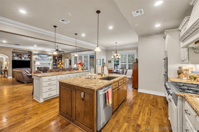 kitchen featuring sink, hanging light fixtures, stainless steel appliances, white cabinets, and a kitchen island with sink