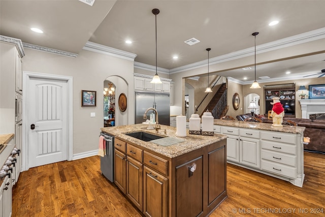 kitchen featuring appliances with stainless steel finishes, a center island with sink, and white cabinets