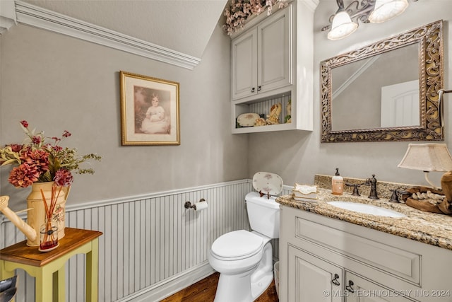 bathroom with wood-type flooring, vaulted ceiling, toilet, vanity, and crown molding