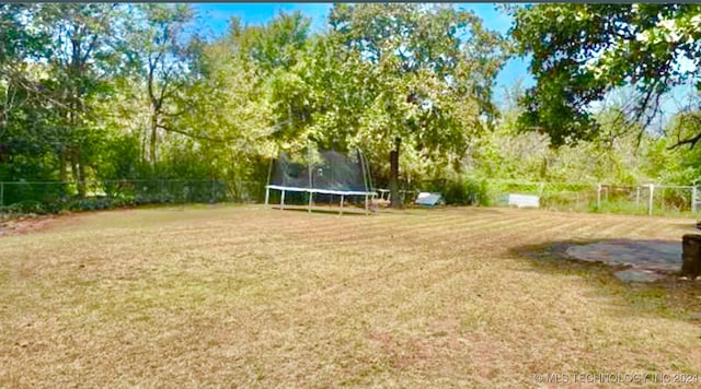 view of yard with a trampoline and fence