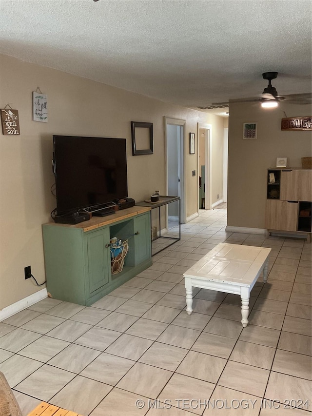 living room featuring light tile patterned floors, a textured ceiling, a ceiling fan, and baseboards