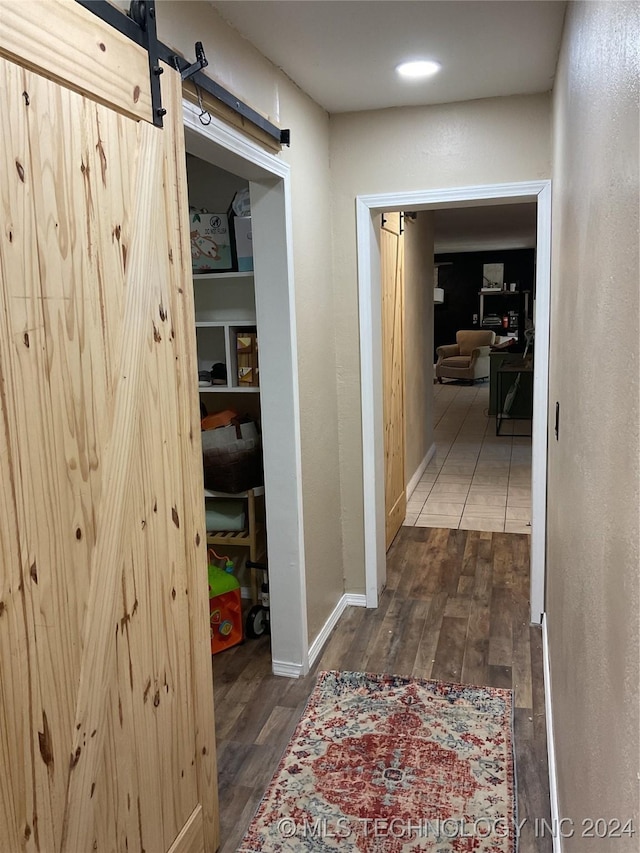 corridor with wood finished floors, baseboards, and a barn door