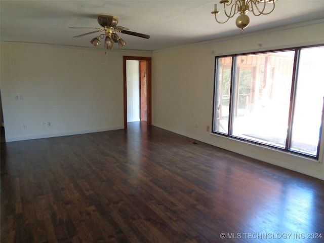 empty room with dark wood-type flooring, crown molding, and ceiling fan with notable chandelier