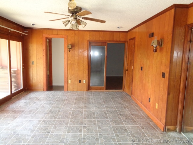 unfurnished room with ceiling fan, ornamental molding, a textured ceiling, and wooden walls