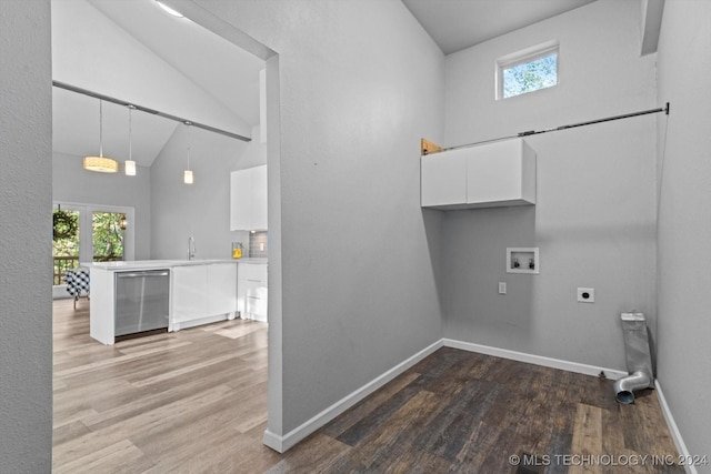 washroom with a towering ceiling, washer hookup, hookup for an electric dryer, and wood-type flooring