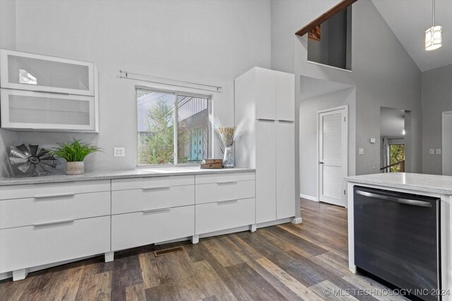 kitchen featuring dark hardwood / wood-style flooring, high vaulted ceiling, stainless steel dishwasher, decorative light fixtures, and white cabinets