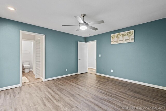 unfurnished bedroom with connected bathroom, ceiling fan, and light wood-type flooring