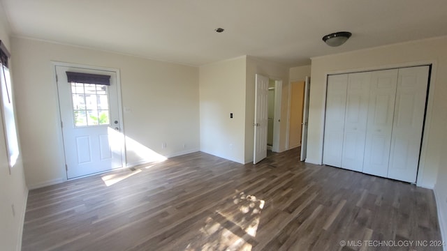 unfurnished bedroom featuring a closet, dark hardwood / wood-style flooring, and ornamental molding