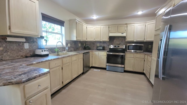 kitchen with stone counters, sink, stainless steel appliances, tasteful backsplash, and cream cabinets