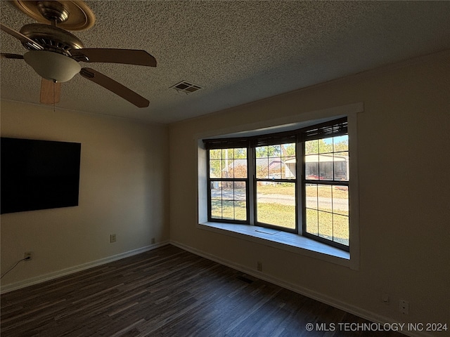 empty room with a textured ceiling, dark hardwood / wood-style floors, and ceiling fan