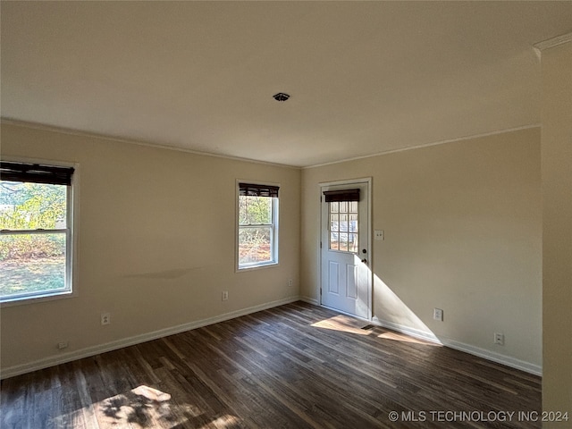 empty room with dark hardwood / wood-style flooring and ornamental molding