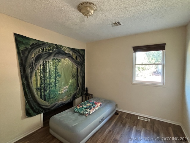 bedroom featuring dark hardwood / wood-style floors and a textured ceiling