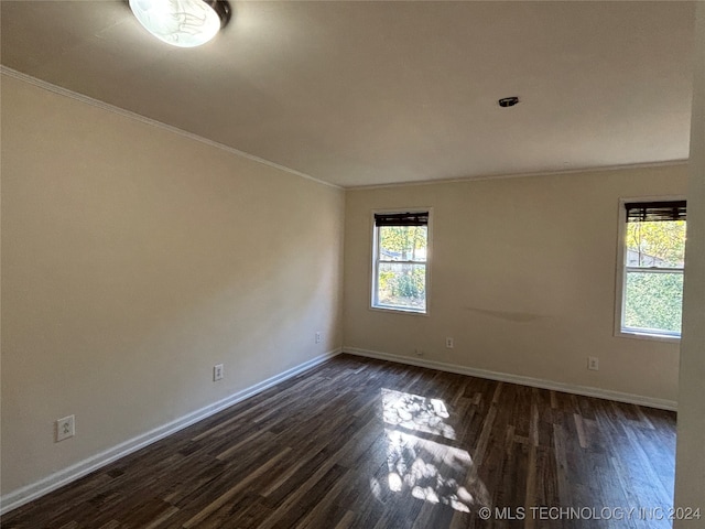 empty room featuring dark hardwood / wood-style flooring and crown molding