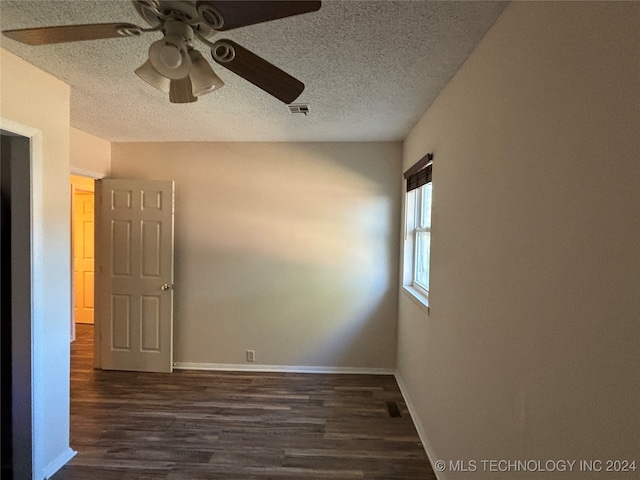 empty room with a textured ceiling, ceiling fan, and dark hardwood / wood-style floors