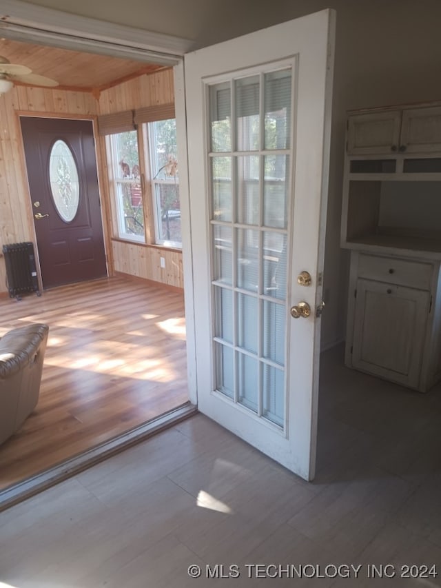 doorway to outside featuring wood walls, hardwood / wood-style floors, ceiling fan, and wood ceiling