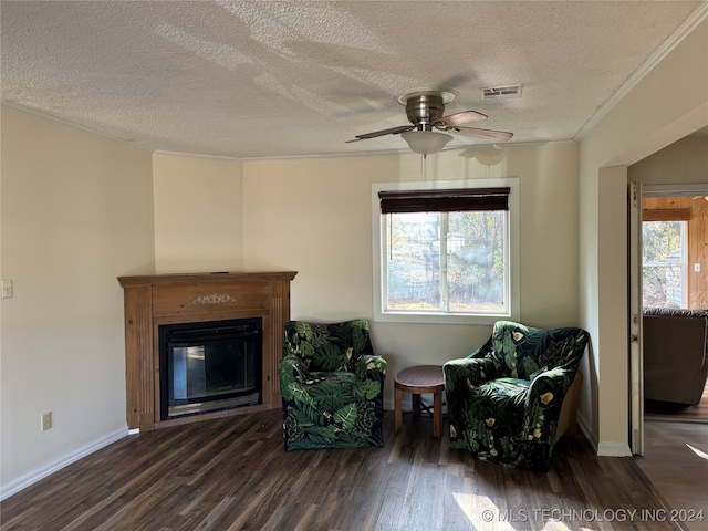 sitting room featuring ceiling fan, dark wood-type flooring, a textured ceiling, and ornamental molding