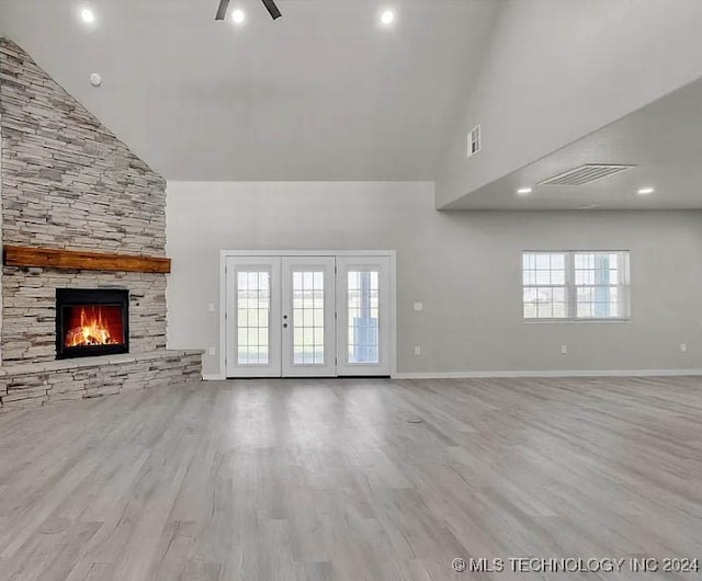 unfurnished living room featuring a wealth of natural light, a fireplace, high vaulted ceiling, and light hardwood / wood-style flooring