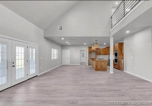 unfurnished living room featuring french doors, high vaulted ceiling, and light hardwood / wood-style flooring