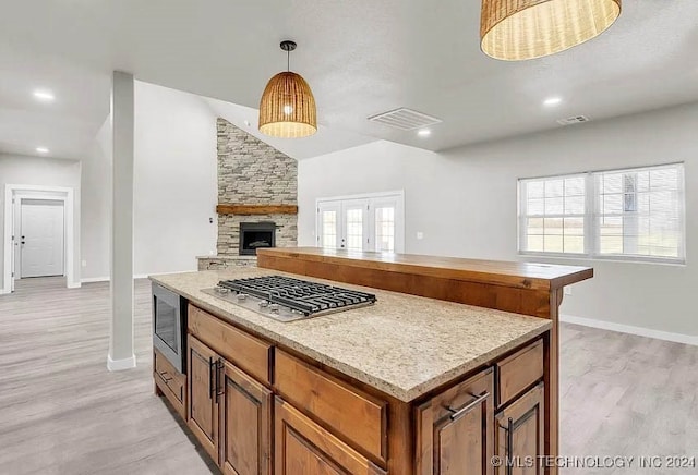 kitchen featuring pendant lighting, lofted ceiling, appliances with stainless steel finishes, and light wood-type flooring