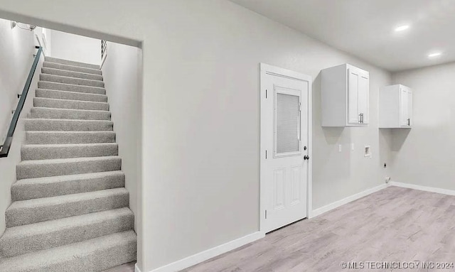 interior space with hookup for an electric dryer, cabinets, hookup for a washing machine, and light hardwood / wood-style flooring